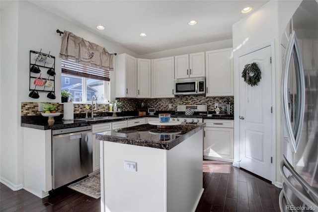 kitchen with sink, dark wood-type flooring, white cabinetry, stainless steel appliances, and a center island