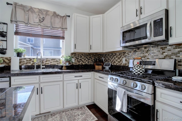 kitchen with sink, dark stone counters, stainless steel appliances, decorative backsplash, and white cabinets