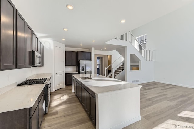 kitchen with light wood-style flooring, a sink, visible vents, dark brown cabinets, and appliances with stainless steel finishes