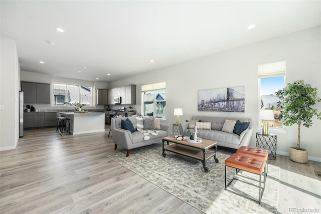 living room featuring light wood finished floors, recessed lighting, and baseboards