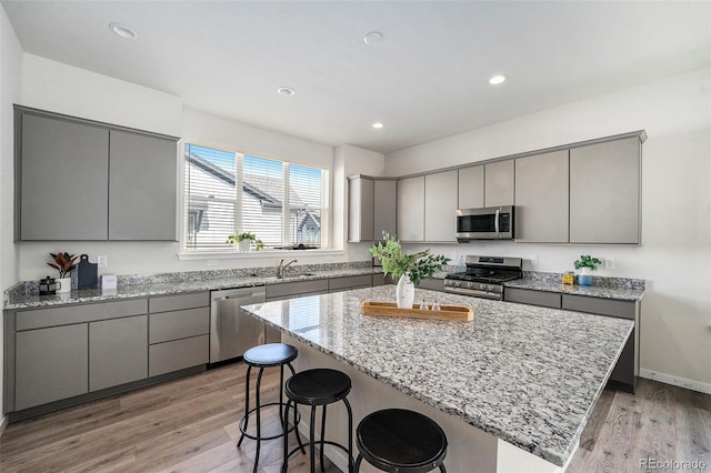 kitchen with a kitchen breakfast bar, gray cabinets, appliances with stainless steel finishes, and a sink