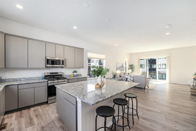 kitchen with a kitchen island, light wood-style flooring, gray cabinets, stainless steel appliances, and open floor plan