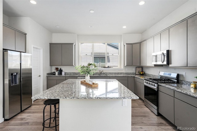 kitchen featuring light wood-type flooring, appliances with stainless steel finishes, a center island, and gray cabinets