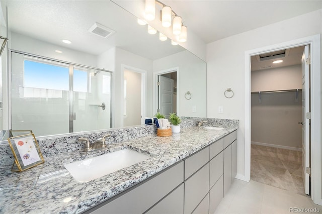 full bath with a spacious closet, visible vents, a stall shower, and a sink