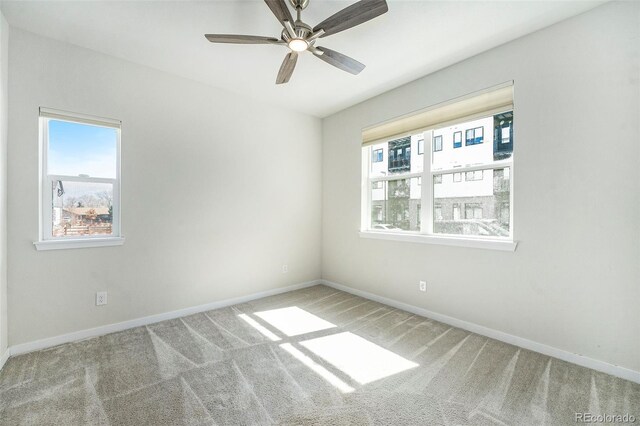 empty room with carpet flooring, a ceiling fan, and baseboards