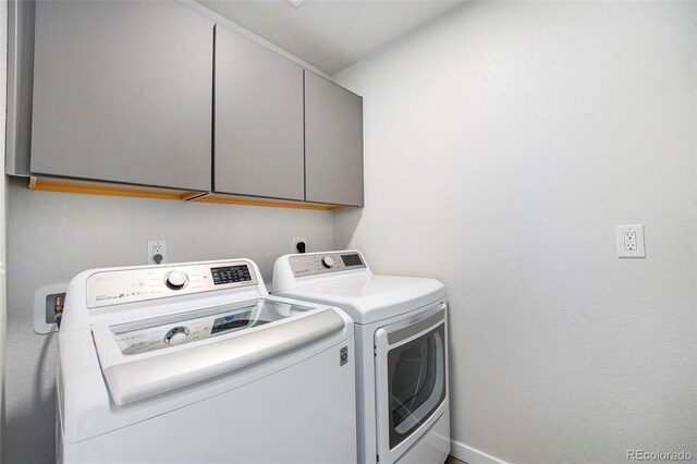 clothes washing area featuring separate washer and dryer and cabinet space