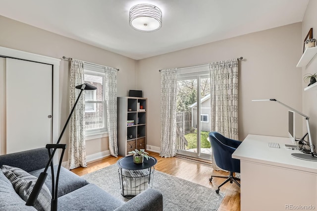 office area with baseboards, light wood-style floors, and a healthy amount of sunlight