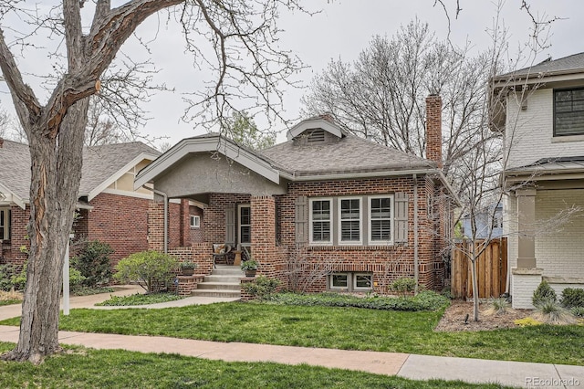 view of front of home featuring fence, a chimney, brick siding, and a front yard