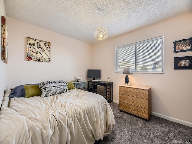 bedroom featuring a textured ceiling and dark carpet