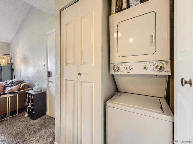 laundry area with a textured ceiling, carpet flooring, and stacked washer / drying machine