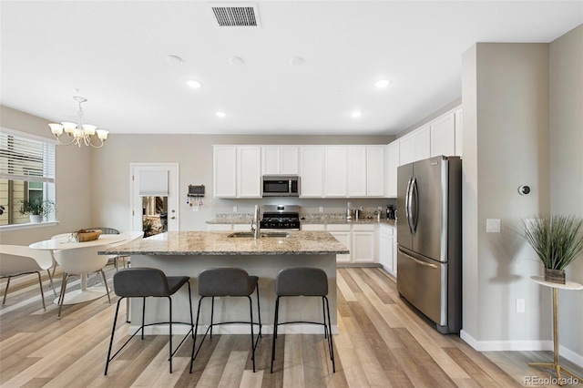 kitchen featuring a sink, visible vents, a notable chandelier, light stone counters, and appliances with stainless steel finishes