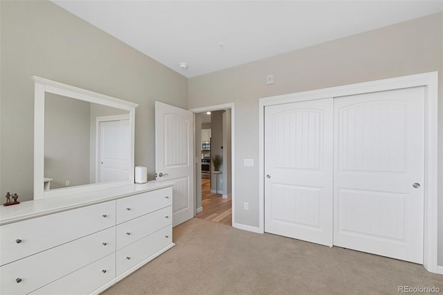 unfurnished bedroom featuring light colored carpet, baseboards, and a closet