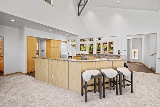 kitchen with stone countertops, light carpet, appliances with stainless steel finishes, a kitchen breakfast bar, and kitchen peninsula