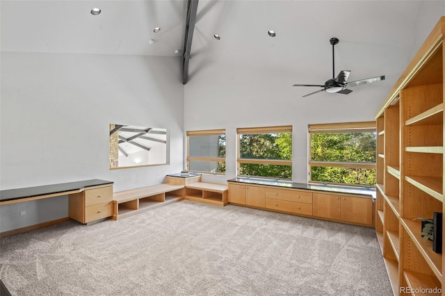 interior space featuring high vaulted ceiling, built in desk, light colored carpet, and ceiling fan