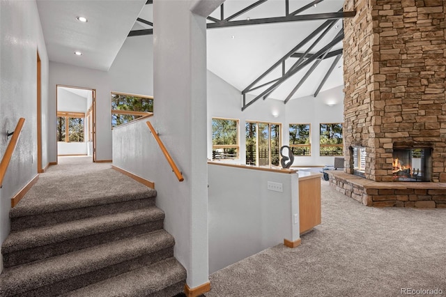 stairs with a fireplace, carpet floors, high vaulted ceiling, and a healthy amount of sunlight