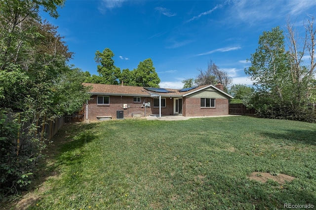 2120 S Ouray St, Aurora, CO 80013 - back of property with roof mounted solar panels, a patio area, a chimney, brick siding, and cooling unit