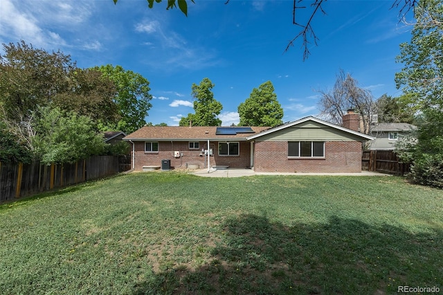 2120 S Ouray St, Aurora, CO 80013 - rear view of house with brick siding, a patio, roof mounted solar panels, and central air condition unit