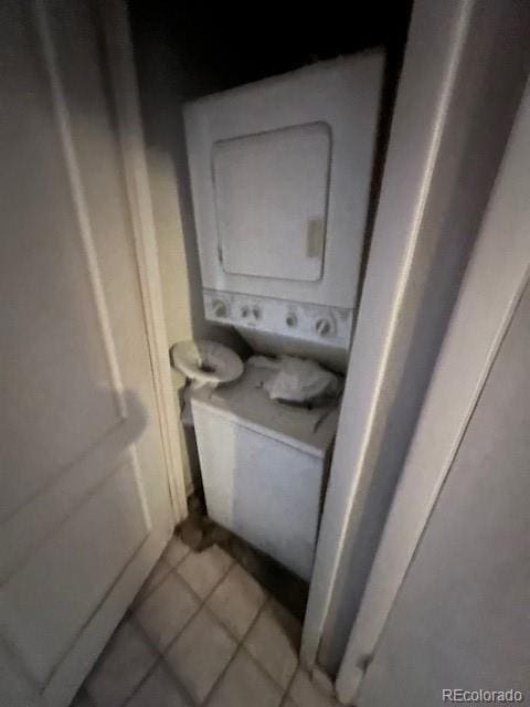 laundry room with light tile patterned flooring and stacked washer / drying machine