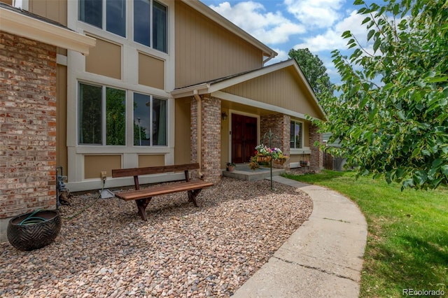 7762 W Ottawa Pl, Littleton, CO 80128 - view of exterior entry with brick siding and a yard