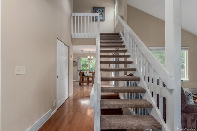 7762 W Ottawa Pl, Littleton, CO 80128 - stairway featuring hardwood / wood-style floors, a chandelier, and a towering ceiling