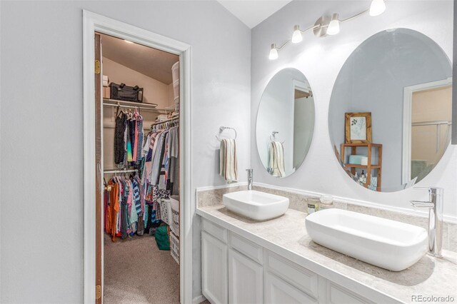 7762 W Ottawa Pl, Littleton, CO 80128 - bathroom featuring double vanity, vaulted ceiling, and a walk in closet