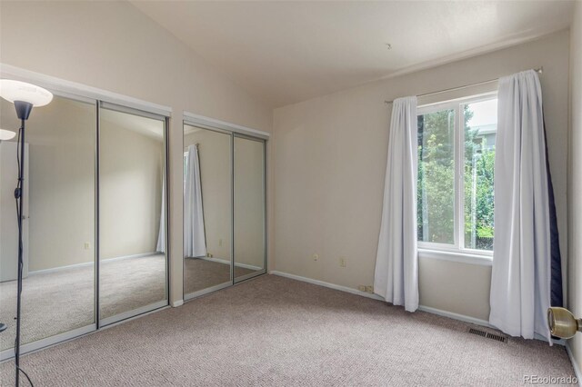 7762 W Ottawa Pl, Littleton, CO 80128 - unfurnished bedroom featuring carpet floors, multiple windows, multiple closets, and lofted ceiling