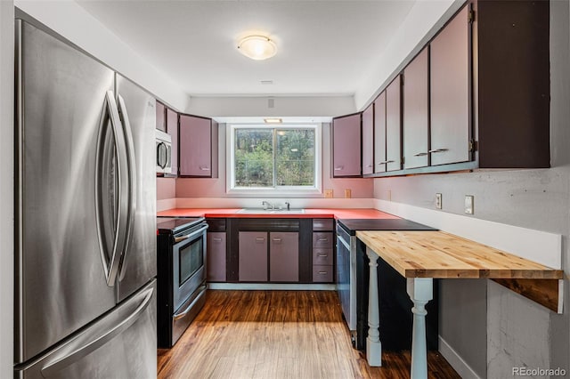 kitchen with butcher block counters, sink, stainless steel appliances, hardwood / wood-style floors, and dark brown cabinets