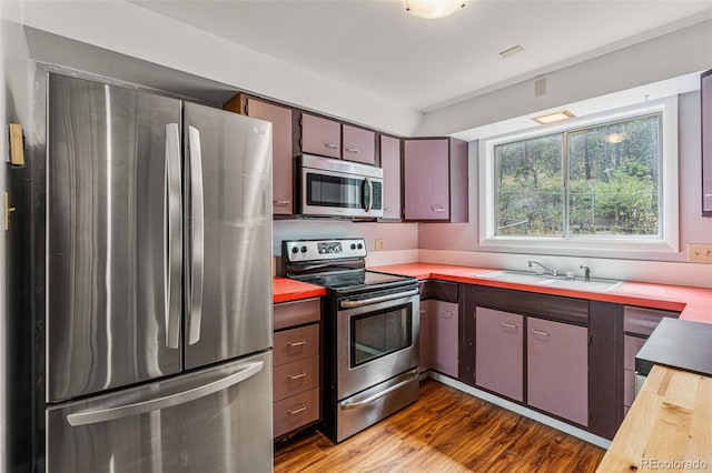 kitchen with butcher block counters, dark hardwood / wood-style flooring, stainless steel appliances, and sink