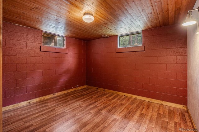 basement with hardwood / wood-style flooring, wood ceiling, and brick wall