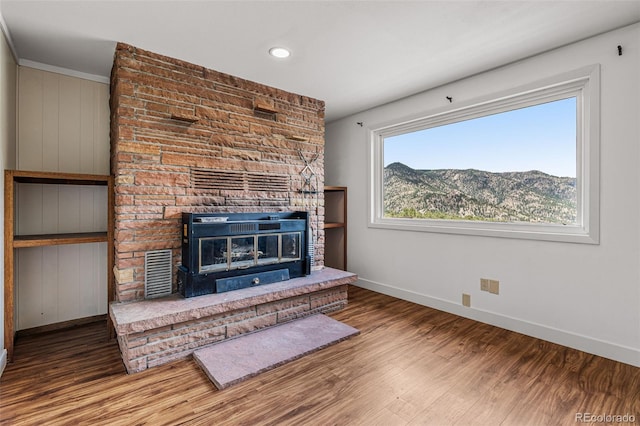 unfurnished living room featuring hardwood / wood-style flooring, a mountain view, and a fireplace