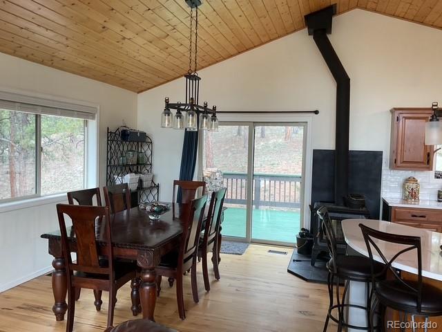 4041 Trout Creed Rd, Woodland Park, CO 80863 - dining room with vaulted ceiling, a wood stove, light wood finished floors, a chandelier, and wood ceiling