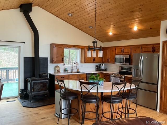 4041 Trout Creed Rd, Woodland Park, CO 80863 - kitchen featuring appliances with stainless steel finishes, a sink, a wood stove, wood ceiling, and light countertops