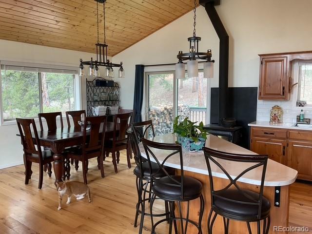 4041 Trout Creed Rd, Woodland Park, CO 80863 - dining room featuring lofted ceiling, healthy amount of natural light, wooden ceiling, light wood-style flooring, and a wood stove