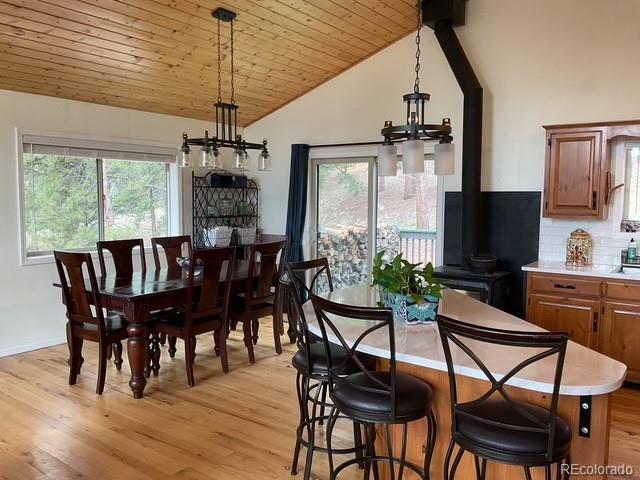 4041 Trout Creed Rd, Woodland Park, CO 80863 - dining space featuring vaulted ceiling, a wood stove, light wood-type flooring, plenty of natural light, and wooden ceiling