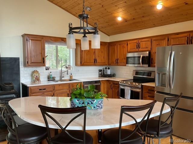 4041 Trout Creed Rd, Woodland Park, CO 80863 - kitchen with stainless steel appliances, a sink, wood ceiling, vaulted ceiling, and brown cabinetry