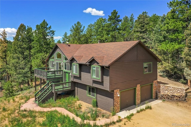 4041 Trout Creed Rd, Woodland Park, CO 80863 - view of front of property featuring a wooden deck, stone siding, an attached garage, stairway, and dirt driveway