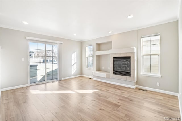 unfurnished living room with ornamental molding, a fireplace, and light hardwood / wood-style floors