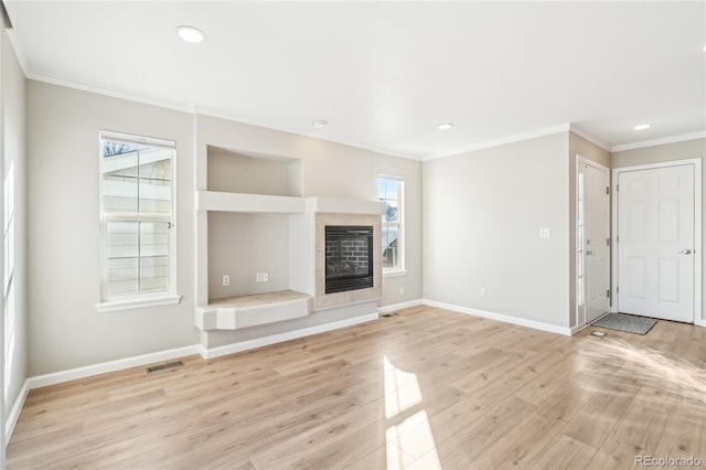 unfurnished living room featuring crown molding, a tile fireplace, and light hardwood / wood-style floors