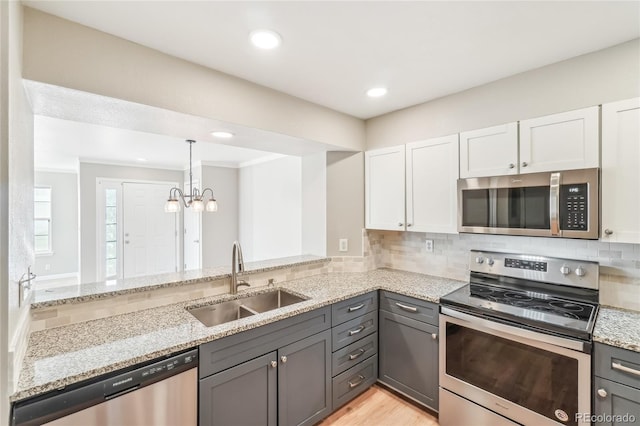 kitchen with sink, gray cabinetry, stainless steel appliances, light stone countertops, and white cabinets