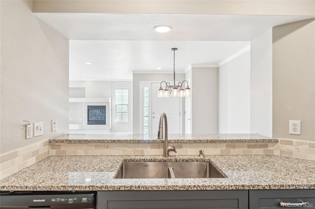 kitchen featuring pendant lighting, sink, crown molding, black dishwasher, and light stone counters