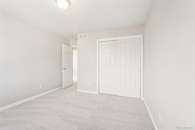 unfurnished bedroom featuring light carpet and a closet