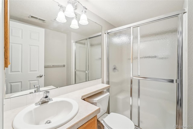 bathroom with vanity, an enclosed shower, and toilet