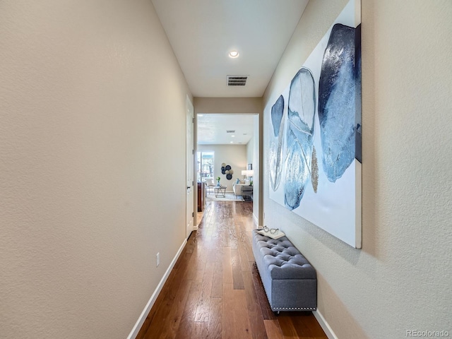 hallway featuring dark wood-style flooring, visible vents, and baseboards