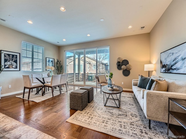 living room with a healthy amount of sunlight, visible vents, baseboards, and hardwood / wood-style floors