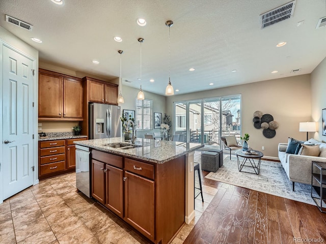 kitchen featuring open floor plan, stainless steel appliances, a sink, and visible vents