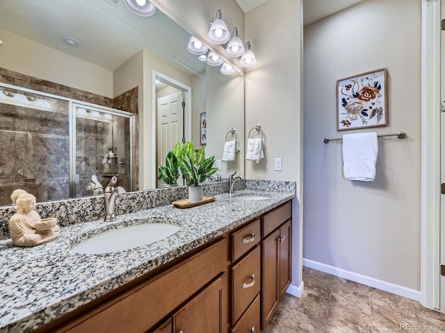 bathroom featuring a sink, a shower stall, baseboards, and double vanity