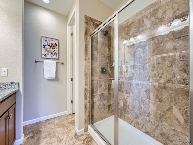 bathroom with a shower stall, vanity, and baseboards