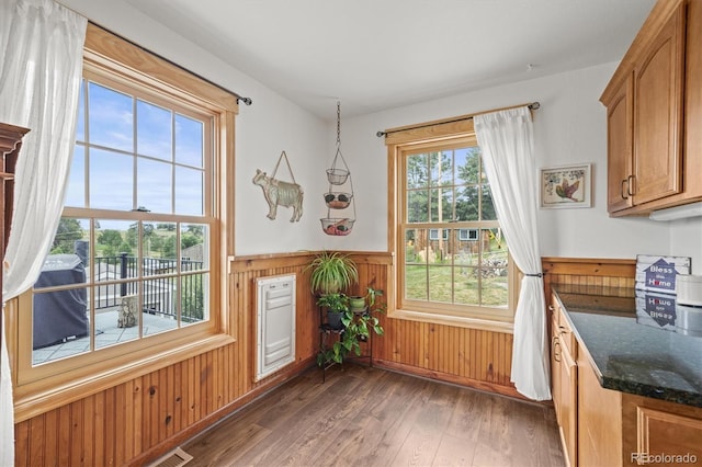 1233 Starling Ln, Elizabeth, CO 80107 - kitchen featuring wainscoting, dark wood-style floors, dark stone countertops, brown cabinets, and wooden walls