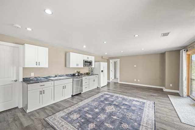 1233 Starling Ln, Elizabeth, CO 80107 - kitchen with appliances with stainless steel finishes, wood finished floors, white cabinets, dark countertops, and recessed lighting