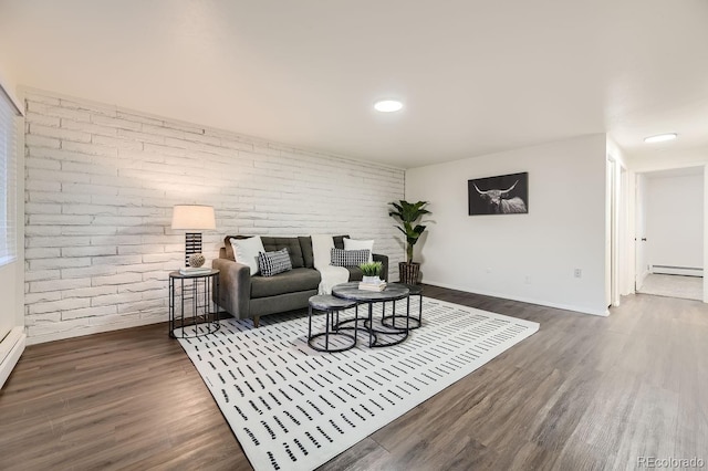 living room featuring brick wall, baseboard heating, and dark wood-type flooring